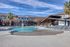 Inviting outdoor pool area with stylish loungers, surrounded by modern apartment buildings and lush palm trees, offering a perfect blend of relaxation and luxury living.