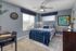 Inviting bedroom with cozy blue accents, natural light, and a functional workspace.