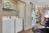 Inviting apartment interior featuring a modern laundry area, elegant bookshelf, and stylish barstools in a cozy atmosphere.