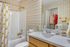 Charming bathroom featuring elegant plaid wallpaper, a cozy white bathtub with floral shower curtain, and a sleek vanity with modern fixtures and stylish decor.