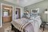 Inviting bedroom with soft green walls, cozy striped bedding, and an artistic map decor. Features an en-suite bathroom and spacious walk-in closet for modern convenience.