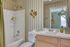 Charming bathroom with modern white tiles, elegant striped wallpaper, and stylish wooden accents. Bright, inviting space perfect for relaxation.