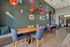Chic and inviting dining area with modern decor, featuring wooden tables, comfortable blue chairs, vibrant red pendant lights, and stylish wall art.