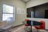 Modern meeting room with chic red chairs, a sleek round table, and contemporary wall art. Ample natural light and stylish decor create an inviting atmosphere.