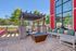 Charming outdoor patio featuring a cozy seating area with colorful cushions, a stylish fire pit, and a rustic pergola against a vibrant red wall.