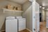 Inviting laundry area featuring modern washer and dryer, complemented by stylish wicker baskets on a sleek shelf, enhancing functionality and charm.