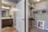 Elegant bathroom adjacent to a spacious walk-in closet with wooden hangers and a stylish wall mirror.