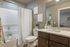 Elegant bathroom with modern fixtures, featuring a sleek white bathtub, stylish dark wood vanity, and tasteful wall decor for a serene atmosphere.