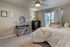 Inviting bedroom with cozy decor, featuring a plush bed and chic vanity under soft natural light.