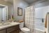 Elegant bathroom design featuring a modern vanity with sleek fixtures, a cozy bathtub with a stylish curtain, and tasteful decor for a serene ambiance.