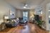 Inviting living room with modern decor, featuring a cozy gray sectional, warm wood flooring, and abundant natural light from large windows.