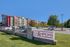 Modern apartment complex with vibrant red accents, spacious parking, and inviting green spaces at Champions Club.