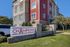 Modern apartment complex with vibrant red and beige exterior, featuring a welcoming Champions Club sign and lush green landscaping.