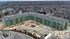 Aerial construction view of a modern apartment complex under construction, surrounded by lush greenery and a charming neighborhood setting.