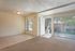 Photo showing carpeted living room adjacent to vinyl tile dining area. The living room is entered by first entering the screened porch.