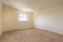 Photo showing carpeted bedroom with 1 window with vertical blinds.