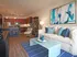 Living room with couch and wood panel flooring, leading into the kitchen.