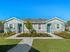 Modern duplex building with two front doors, landscaped garden, and a pathway under a clear blue sky.