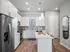 Contemporary kitchen with sleek white cabinetry, stainless steel appliances, and stylish island seating.