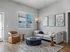 Stylish living room with contemporary decor, featuring a beige sofa, leather chair, and abstract artwork.