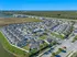 Aerial view of a modern residential community with well-planned roads, green spaces, and a nearby water body.