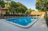 Inviting swimming pool surrounded by lush greenery and modern apartment complex.