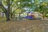 Vibrant playground set amidst lush trees with picnic area, ideal for families.