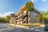 Bright apartment building with palm trees and spacious outdoor balconies.