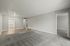 Bright and open living room with plush carpet and wooden flooring, leading to a contemporary kitchen.