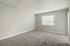 Spacious bedroom with soft carpet and large window featuring natural light.