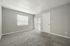 Bright, empty room with carpet flooring, large window, and sliding glass door.