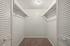 Bright walk-in closet with ample shelving and soft carpeting.