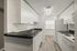 Contemporary kitchen with white cabinetry, black countertops, and stainless steel fixtures.