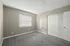 Bright, unfurnished bedroom with soft grey carpet, a large window, and a spacious closet.