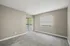 Spacious room with plush carpet, natural light from large window and balcony doors, and neutral walls.