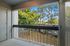 Charming apartment balcony with a scenic view of lush, green trees and a peaceful residential area.