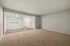 Bright open-concept living room with carpeted flooring and elegant neutral walls.