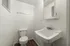 Elegant minimalist bathroom featuring a white sink, toilet, and wall mirror with soft lighting.