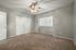 Bright, empty bedroom with a ceiling fan, plush carpeting, and large window offering abundant natural light.