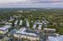 Aerial view of a lush green neighborhood with modern apartment complexes and a swimming pool.