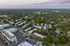 Aerial view of a vibrant residential community surrounded by lush greenery and ample parking space.