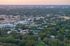 Aerial view of a vibrant residential community with lush greenery and modern apartment buildings, captured at sunset.