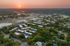 Aerial view of a vibrant urban community at sunrise, with lush greenery and modern buildings.