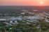 Aerial view of a vibrant urban neighborhood at sunset, showcasing extensive greenery and modern buildings.