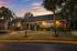 Charming brick bungalow with a beautifully landscaped front yard, set against a stunning sunset.
