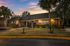 Inviting brick home surrounded by lush greenery under a vibrant sunset sky.
