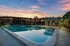 Charming apartment complex with a sparkling pool at sunset, inviting ambiance.