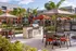 Vibrant outdoor communal area with barbecue, dining tables, umbrellas, and lush landscaping.