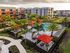 Aerial view of a modern apartment complex featuring a stylish swimming pool area with orange cabanas and lush palm trees.