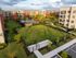 Lush courtyard view of a modern apartment complex with landscaped gardens and a communal pool.
